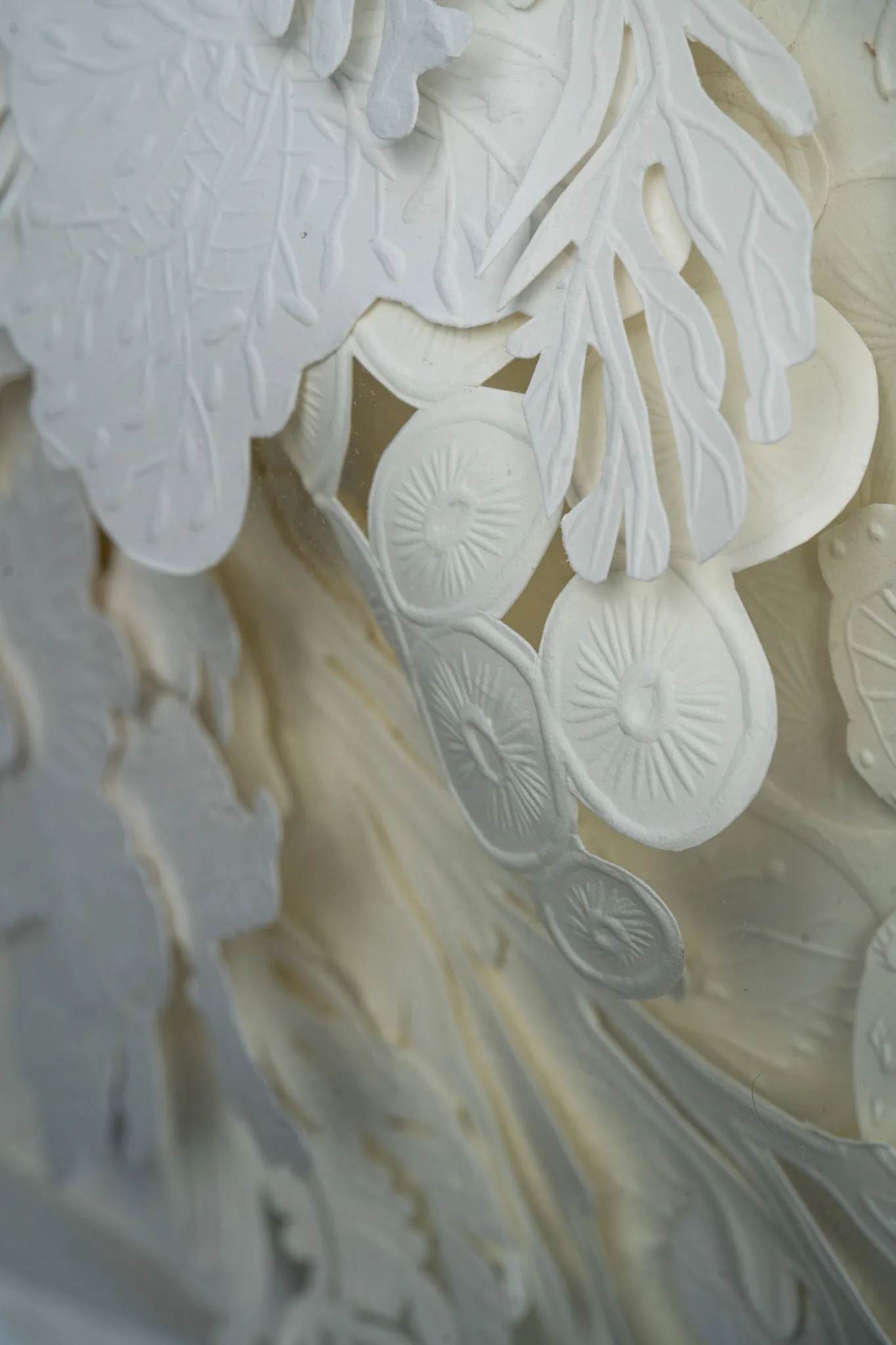 Angled detail of Mar Blanco. A branching form and a string of embossed discs stand off the sheet over soft folds of paper.