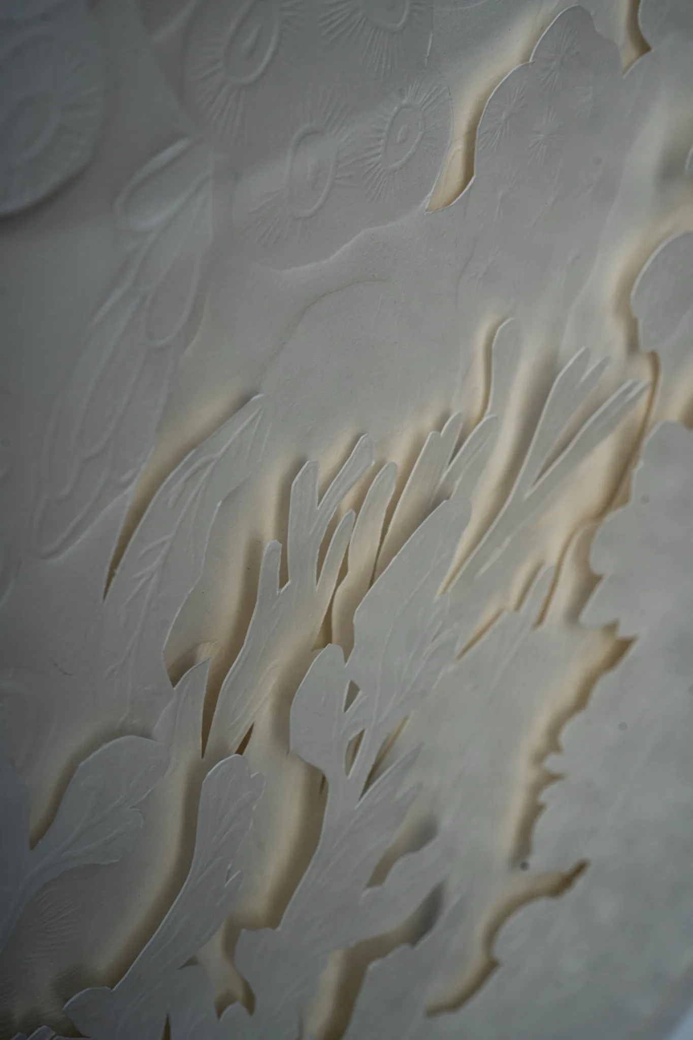 Raking light detail of Mar de Seto. Long tongue-like cuts in the paper curl open, each lined with a warm band of shadow.