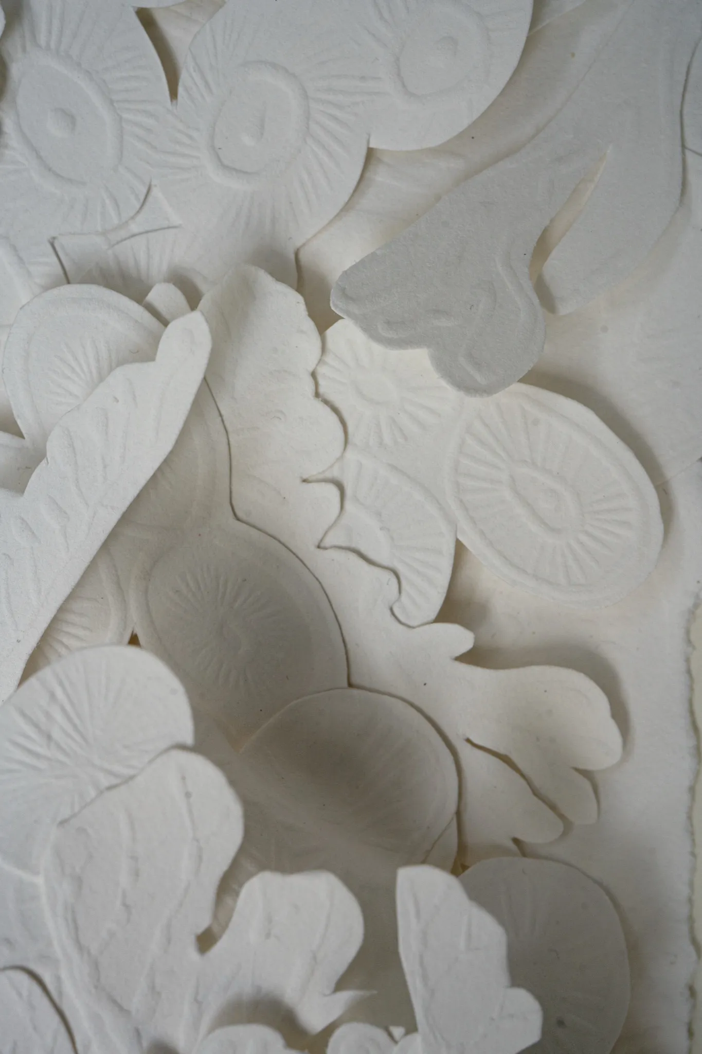 Close detail of Mar de Weddell. Embossed discs with radiating lines overlap rounded cut shapes and a pale leaf.